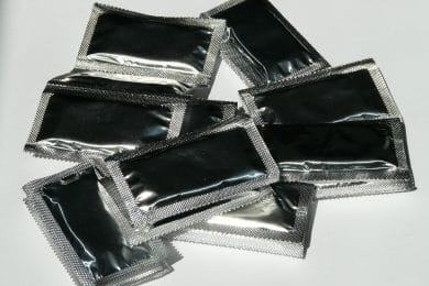 Sølvfarvede kondomer ligger på bord