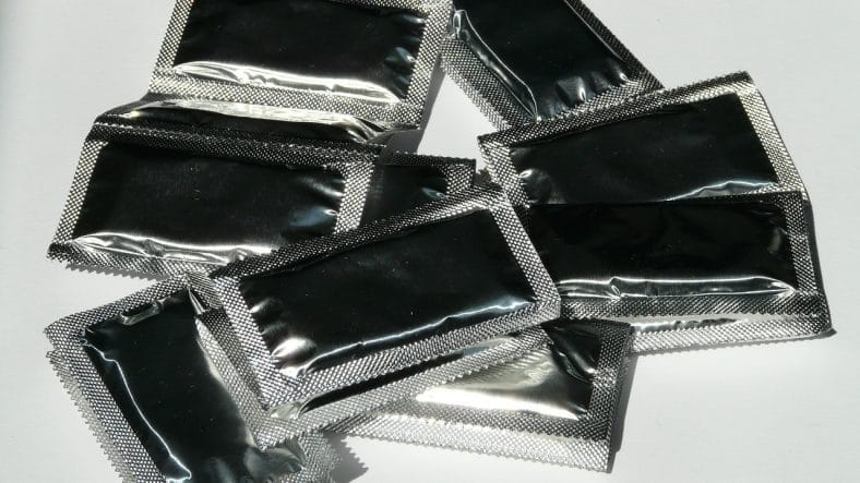 Sølvfarvede kondomer ligger på bord