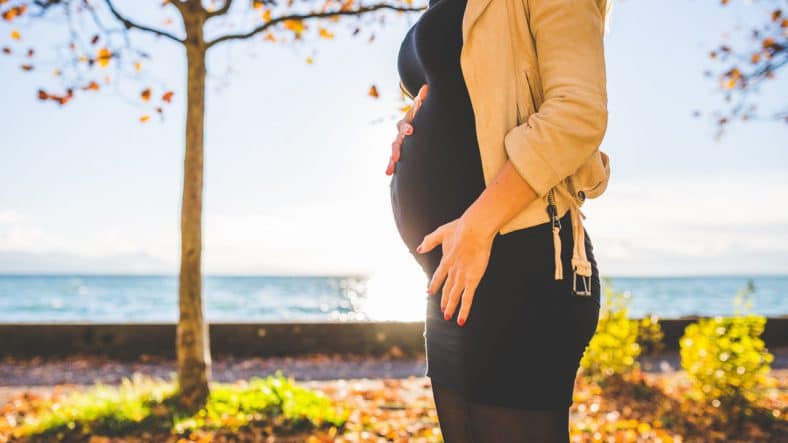 Gravid dame ved havet i solen