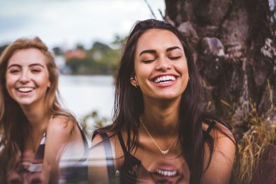 To glade damer smiler og hænger ud ved en sø